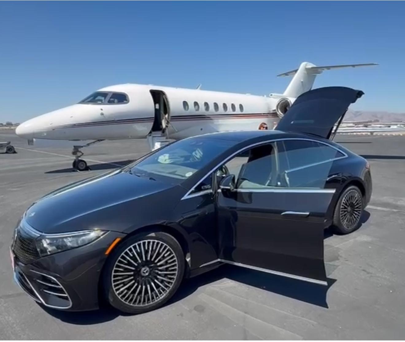 Jet Car Limo's black Mercedes-Benz EQS parked with its rear door open beside a private jet on the tarmac