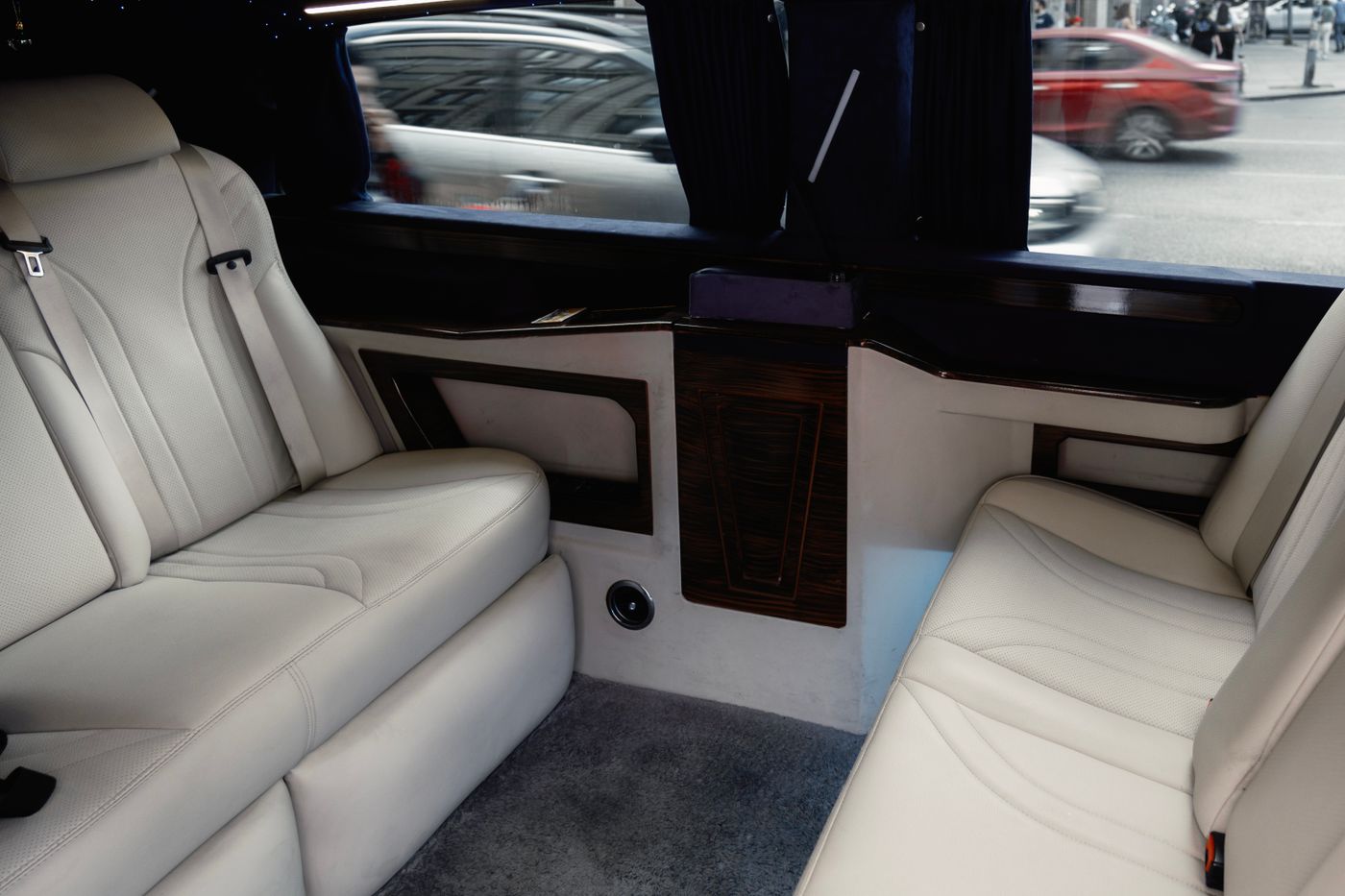 Rear cabin of a limousine with cream leather seating and polished wood trim